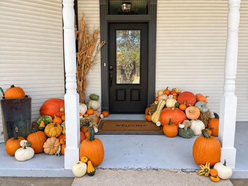 A real Picture Perfect Pumpkins porch display with pumpkins, gourds, hay bales and cornstalks